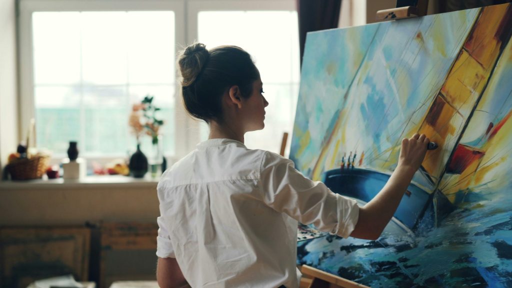A woman paints on a canvas.